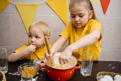 Sister and brother cook in the kitchen, knead the dough, easter holiday