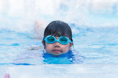 Happy children smiling cute little girl in sunglasses in swimming pool.