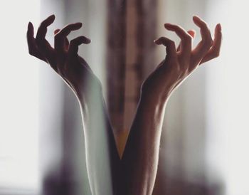 Close-up of silhouette hand against window over white background