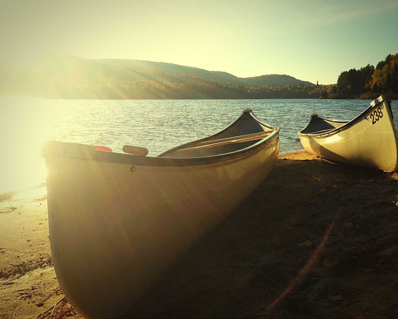 transportation, water, nautical vessel, mode of transport, mountain, sea, boat, scenics, tranquility, moored, tranquil scene, sky, sunlight, beauty in nature, beach, mountain range, nature, sun, travel, sunset