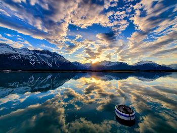 Scenic view of lake and mountains against sky at sunset