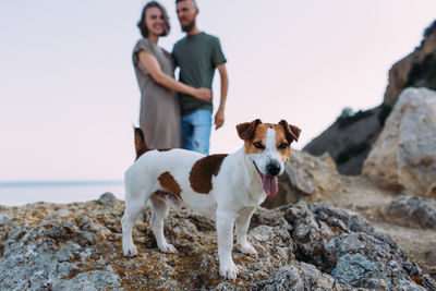 Happy couple with favourite pet. young man and woman have walk near sea.