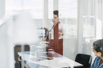 Businesswoman showing digital tablet to colleagues