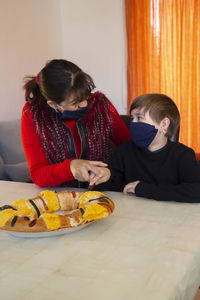 Full length of mother and daughter while sitting on table