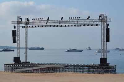 Seagulls on pier by sea against sky