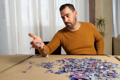 Man sitting with jigsaw puzzle on table at home