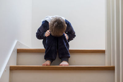 Full length of a man sitting on wall at home