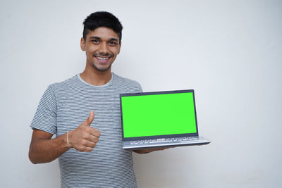 Portrait of smiling young man standing against white background