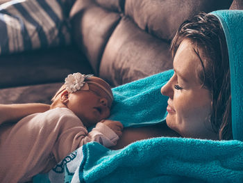 Close-up of mother with baby relaxing on bed at home