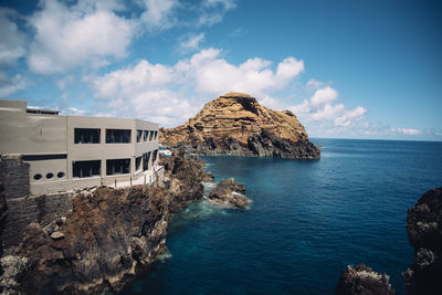 Rock formation by sea against sky