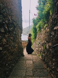 Rear view of woman walking by wall