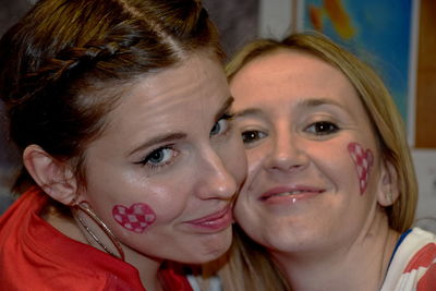 Close-up portrait of smiling female friends with heart shapes on cheeks