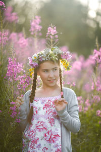 Girl looking away while standing against flowering plant