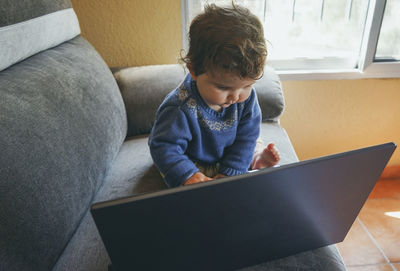 Boy sitting on sofa at home