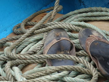 High angle view of old slippers by rope on boat deck