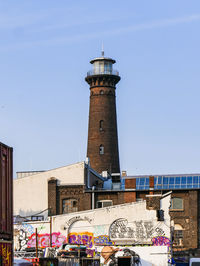 Low angle view of lighthouse against buildings in city