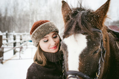 Close-up of beautiful woman with horse on field during snowfall