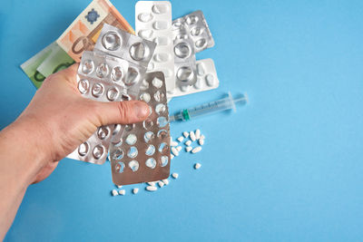 Close-up of hand holding blue ring over white background