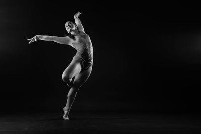 Low section of woman jumping against black background