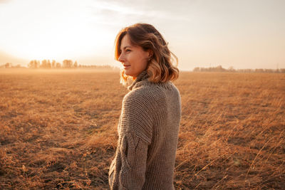 Side view of smiling woman standing on field