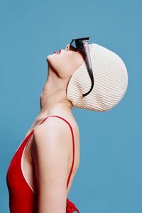 Young woman wearing hat against blue background