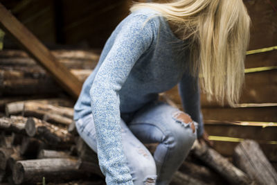 Young woman sitting on stacked logs in barn