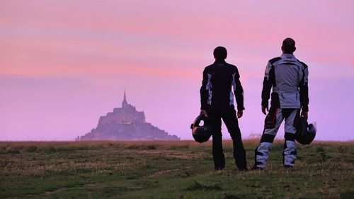 Rear view of men standing on field against sky