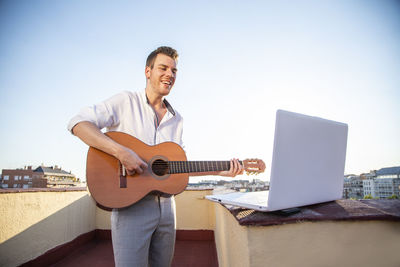 Handsome young singer performing for his fans on social media from the roof of his house during quarantine