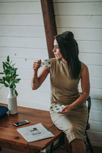 Woman drinking coffee while sitting on table