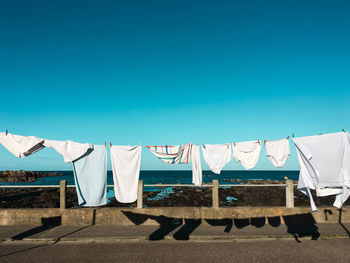 Clothes drying on beach against clear blue sky