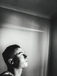 Portrait of young man looking away against wall