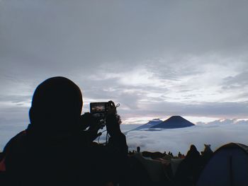 Rear view of woman photographing sky