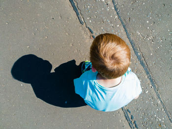 High angle view of boy standing with shadow on street