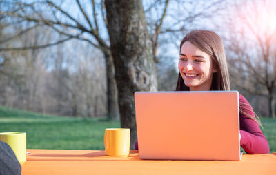 Young woman using laptop while sitting on table