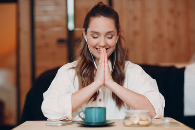 Young woman holding coffee while sitting on table