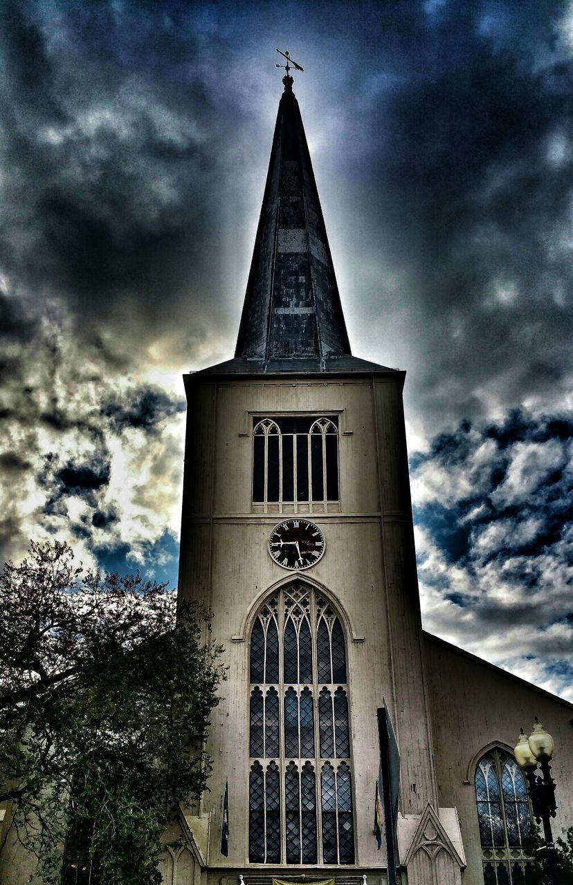 sky, architecture, low angle view, religion, building exterior, built structure, cloud - sky, cloudy, church, place of worship, spirituality, cross, cloud, tower, tree, clock tower, cathedral, outdoors