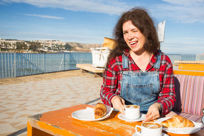 Young woman smiling while sitting on table