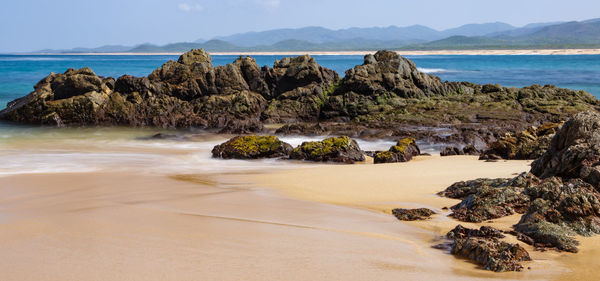 Scenic view of rocks on beach against sky