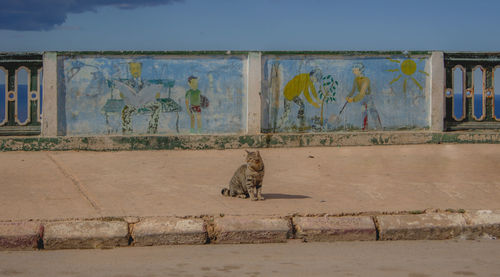 Graffiti on wall by beach against sky