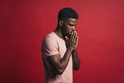 Young man holding red while standing against orange background