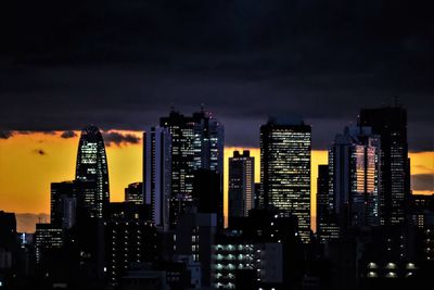 Illuminated buildings in city against sky at night