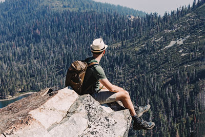 Man sitting on the cliff with a beautiful view to mountains. backpacking, hiking, summer activities