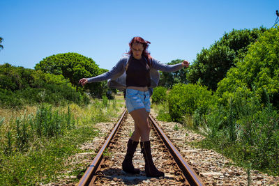 Woman standing on railroad track amidst trees
