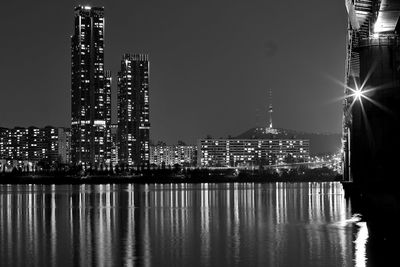 Illuminated modern buildings in city against sky at night