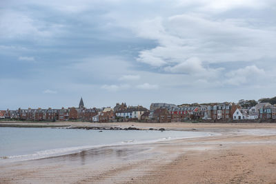 View of beach and buildings against cloudy sky