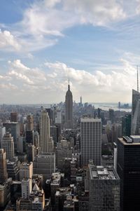 Aerial view of buildings in city against cloudy sky