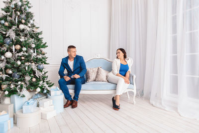 Couple sitting on sofa by christmas tree at home