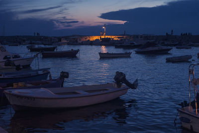 Sailboats moored on sea against sky at sunset