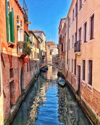 Arch bridge over canal amidst buildings in city