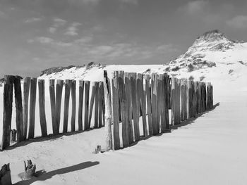 Wooden posts on beach against sky during winter